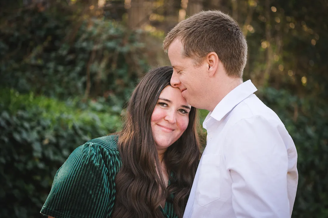 Evan kissing Brianna's forehead in a garden portrait